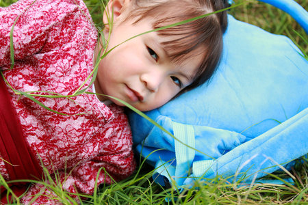 Cute little girl lying on the grassの写真素材