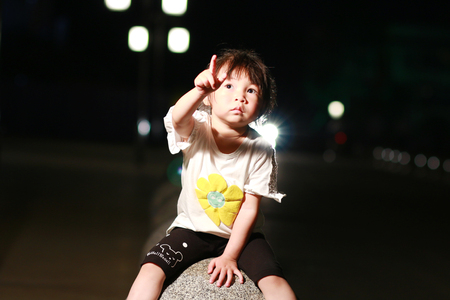 Little girl sitting on a stone benchの写真素材