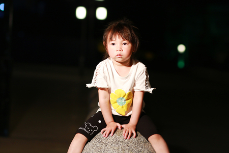 Little girl sitting on a stone benchの写真素材