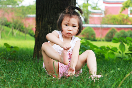 Little girl sitting on the grassの写真素材