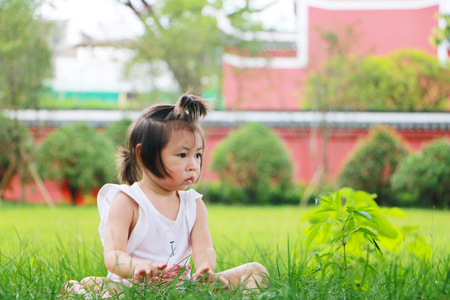 Cute little girl sitting alone on the grassの写真素材