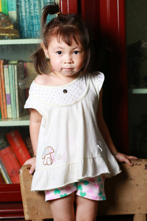 Cute little girl holding a chairの写真素材
