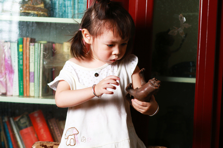 Cute little girl standing on a chair playing woodcarving toyの写真素材