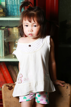 Cute little girl standing in a chair staring at the cameraの写真素材
