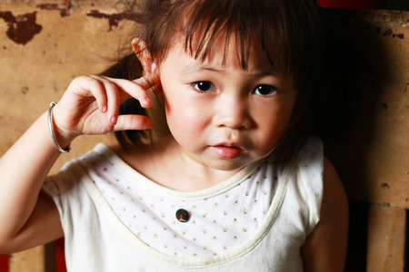 Cute little girl sitting on a chair smiling and looking at the cameraの写真素材
