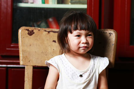 Cute little girl sitting on a chairの写真素材