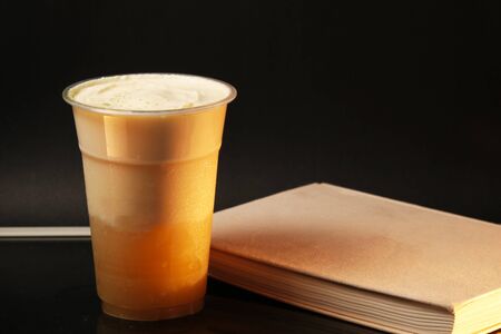 Milk tea with book close-up on the tableの写真素材