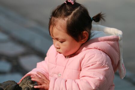 Little girl stroking an animal statueの写真素材