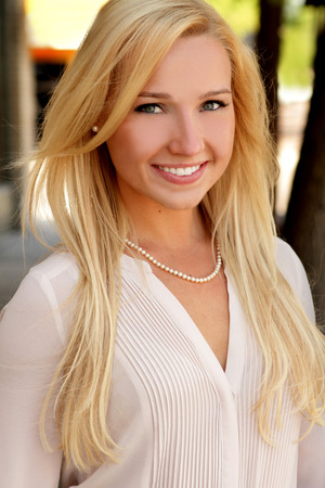 Pretty young blonde woman smiling outdoors portraitの写真素材