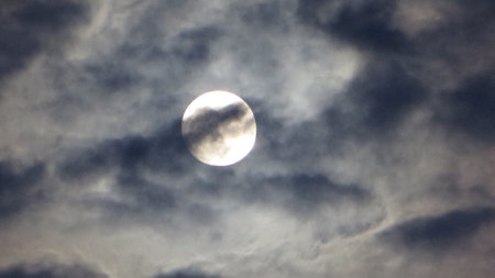 Full moon in the dark sky with clouds. Natural background and texture.