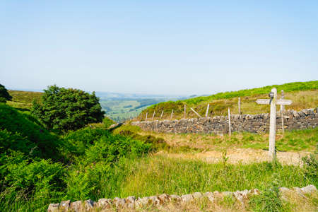 Signpost in Curbar Gap showing the way to Baslow Edge and Curbar Edge on a hazy summer morning