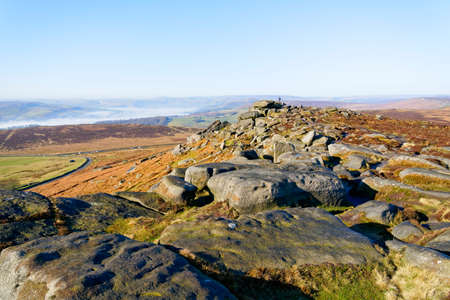 Across the rocks and heather of Stanage Edge to the distant foggy valleys of the Peak Districtの写真素材