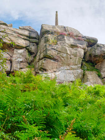 Birchen Edge cliff face with Helsons monument perched on top rises up from dense ferns.の写真素材