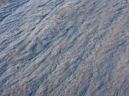 Close up of the surface of a weathered and stained piece of gritstone rock. Ridges and grooves run...