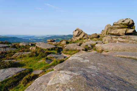 High on a hill in the Derbyshire Peak District large gritstone boulders and outcrops stand eroded in to strange shapesの写真素材