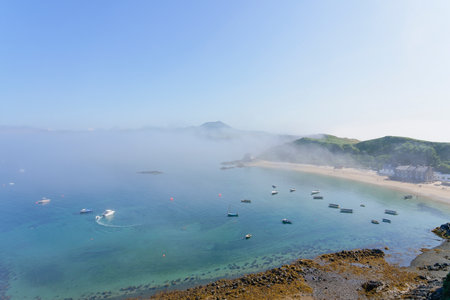 A low fog swirls across Porthdinllaen bay and beach on a summer afternoon.の写真素材