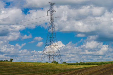 a power line tower rises high above farmland in central minnesotaの写真素材