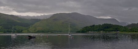a panoramic view of the glencoe marina on loch leven, surrounded by the beautiful mountains of the scotish highlands, glencoe, scotland.の写真素材