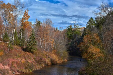 a fisherman wades through the amnicon river in northwestern wisconsin, autumnの写真素材
