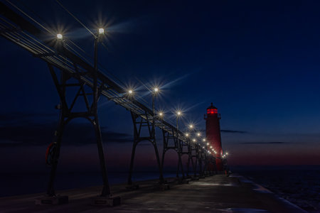 Lights illuminate the Grand Haven, Michigan, pier and lighthouse as the sky turns dark blueの写真素材