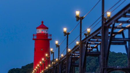 The red lighthouse and catwalk at Grand Haven, Michigan, with lights on at dusk on Lake Michiganの写真素材