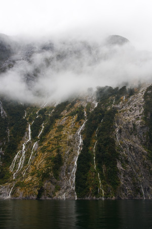 Boat cruise past cliffs in beautiful milford soundの写真素材