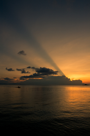 Boat drifting calmly on the ocean during a tropical ocean sunsetの写真素材