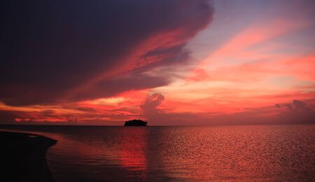 Tropical sunset over island silouetteの写真素材