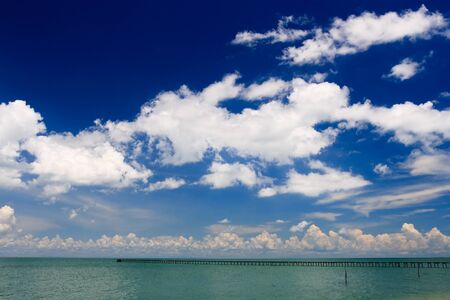 Deep blue sky over ocean pier stretching into turquoise seaの写真素材