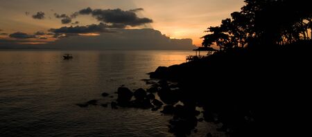 Boat drifting calmly on the ocean during a tropical ocean sunsetの写真素材