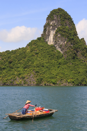Floating market seller in Halong Bay, leaving for the next boat, Vietnamの写真素材