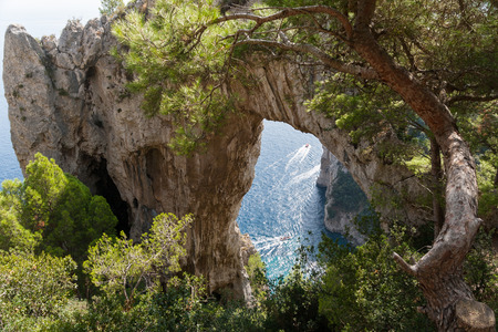 Boats pass under a Natural Arch in Capri, Italyの写真素材