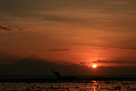 Sunset over Batur Volcano, Bali, seen from the Gilli Islands with shipwreck in foregroundの写真素材