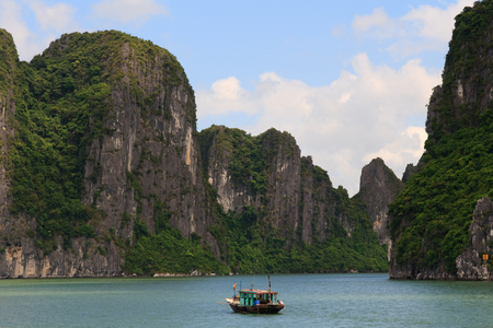 Fishing Boat cruises through the halong bay cliffs, Vietnamの写真素材