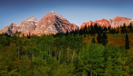 Maroon Bells peaks capture sunrise light with aspen forest in foreground, near Aspen Coloradoの写真素材