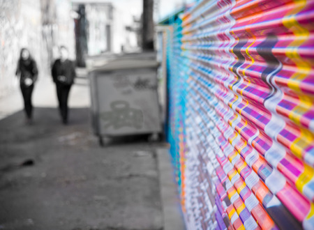 Two people in alleyway with colorful wall art and dumpsterの写真素材