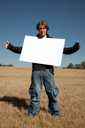 A 21 year old guy hold up a blank sign that you can use to place your message on.の写真素材