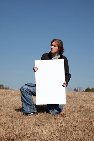 A 21 year old guy hold up a blank sign that you can use to place your message on.の写真素材