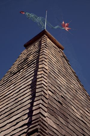Beautiful weathervane sits atop a shake roof with a deep blue sky above.の写真素材