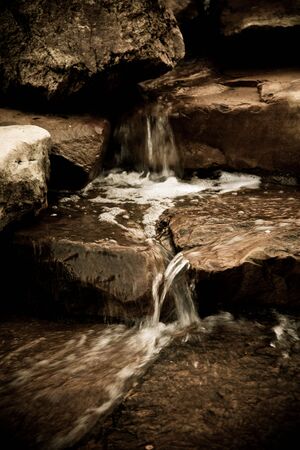 Water cascades over the stones and rocks on its way downstream.の写真素材