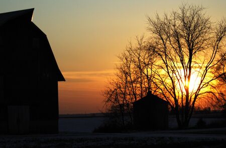 Silhouette of Barn and Shed at Sunsetの写真素材