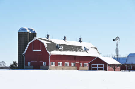Big red barn and windmill in winter.
