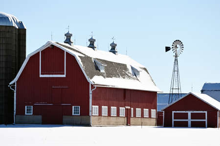 Red barn and windmill in winter.の写真素材