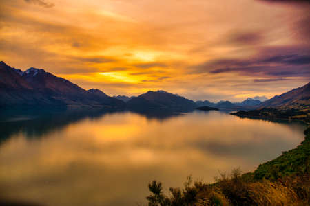 Dramatic vibrant Orange skies and cloudscape of sunset at Lake Wakatipuの写真素材