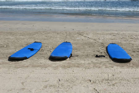 A trio of blue surf boards lying on the sand on Kuta Beach Bali Indonesiaの写真素材