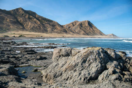 The dramatic and extreme terrain of the rocky coastline the surf beach and the hillsの写真素材