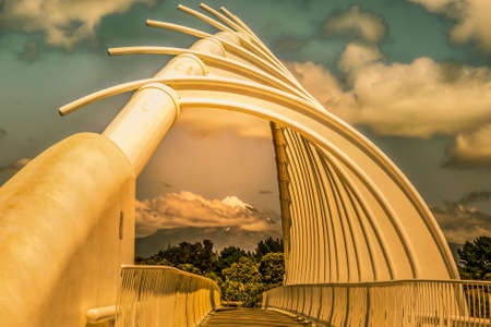 Golden light lighting up the architecturally beautiful  bridge with the snow capped volcanic mountain in the distanceの写真素材