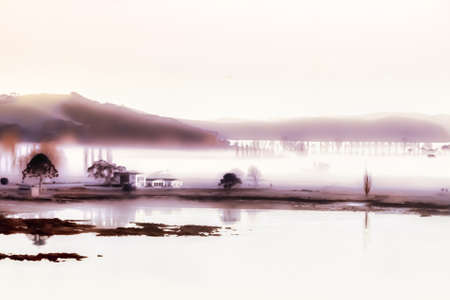Hazy sunrise at the bay of islands coast as the early morning fog and mist stars to liftの写真素材