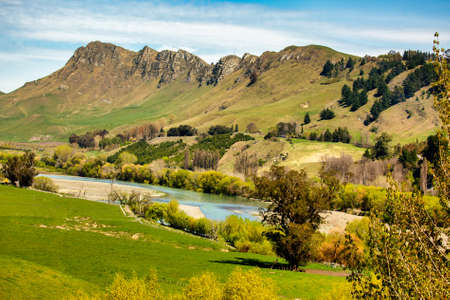 Lush farming and agricultural fields below the dramatic ridge with a river flowing between the trees