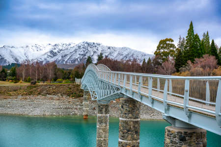 The stunning pedestrian footbridge over he amazing vivid blue water in Scott Pond at Lake Tekapoの写真素材